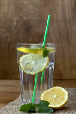 Limonlu kokteyl. Yaz içkileri. Limonlu limonata ve naneli taze yaprak. Ev yapımı soğuk serinletici içecek ya da kırsal ahşap zemin üzerinde çuval bezi olan buzlu su. Boşluğu kopyala.