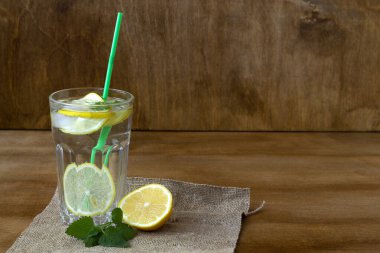 Odunlu mojito kokteyli. Yaz içkileri. Limonlu bir bardak limonata ve naneli taze yaprak. Ev yapımı soğuk serinletici içecek ya da kırsal ahşap zemin üzerinde çuval bezi olan buzlu su. Boşluğu kopyala.