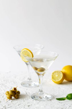 Kokteyl ve beyaz arka planda zeytinli iki martini bardağı. Limonlu ve yeşil naneli Margarita kokteyli. kopyalama alanı. Alkollü. dikey.