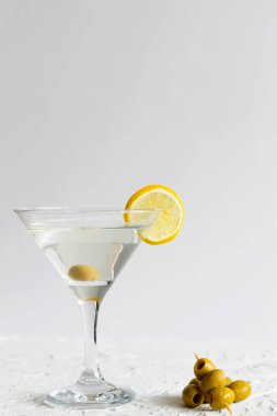 Limonlu martini. Kokteylli martini bardağı ve beyaz arka planda zeytin. Limonlu ve limonlu kokteyl. kopyalama alanı. Alkollü. dikey