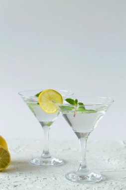 Alkollü. Beyaz arka planda kokteylli iki martini bardağı. Margarita kokteyli, limonlu ve naneli olsun. kopyalama alanı. dikey