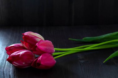 Bir buket lale. Siyah arka planda parlak bahar laleleri. Uzayı kopyala Siyah masada kırmızı laleler. en üstteki görünüm.