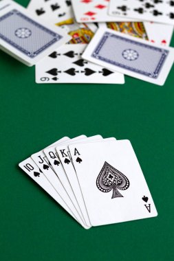 Poker kartları. Floş royal. Yeşil masada mavi güverteli kağıt oynuyoruz. Yeşil bir kumarhane masasında kart kombinasyonu. poker. Üst Manzara. dikey