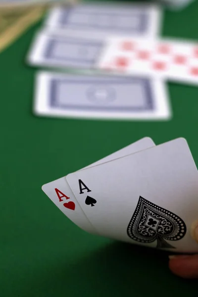 hand shows a card red and black aces in casino. playing cards with blue deck on the green table. combination of cards on a green casino desk background.copy space. vertical. poker