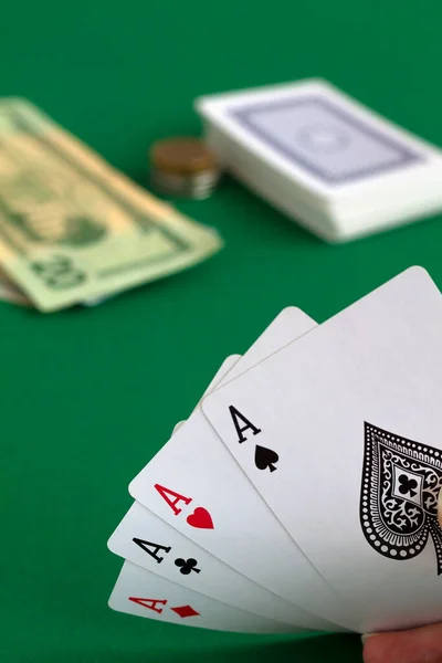poker cards and money.four aces in the hands. playing cards with blue deck on the green table. combination of cards on a green casino desk background.