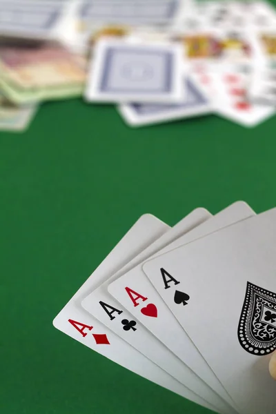 poker cards and chips in the game.four aces in the hands. playing cards with blue deck on the green table. combination of cards on a green casino desk background.copy space. vertical