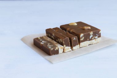 Beyaz masada fındıklı ve fıstıklı çikolata ve süt şerbeti kesiyorum. Beyaz arka planda Türk ve Arap şerbetinin geleneksel tatlılığı. Fotokopi alanı olan tatlı.