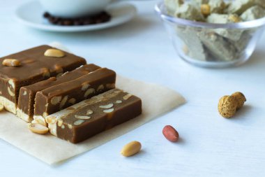 Beyaz masada fındıklı ve fıstıklı çikolata ve süt şerbeti kesiyorum. Beyaz arka planda Türk ve Arap şerbetinin geleneksel tatlılığı ve halva. Tatlı fotokopi alanı