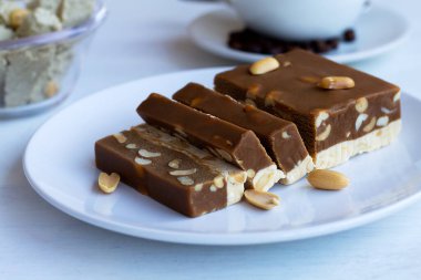 Beyaz masada fındıklı çikolata ve süt şerbetini yakın plan kesim. Tabakta Türk ve Arap şerbetinin geleneksel tatlılığı ve halva ayçiçeği var. Tatlı ve kahve. Kopyalama alanı..