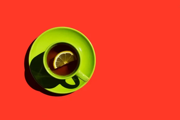 绿杯和茶碟 红底有红茶和黄色柠檬或咖啡 复制空间 顶部视图 — 图库照片