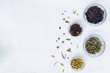 Yemek pişirmek için kuru baharatlar. Yemek malzemeleri beyaz masanın üzerinde. Otlarla düzleştirilmiş arka plan, kopyalama alanı olan baharatlar. en üstteki görünüm.
