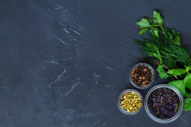 Bitkiler ve baharatlar. Pişirmek için taze ve kuru baharatlar. Yemek malzemeleri siyah masanın üzerinde. Yeşil otlar, baharatlar ve kopyalama alanı olan sarımsaklı düz bir zemin. en üstteki görünüm.