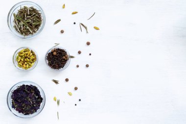 Ahşap bir masada baharatlar. Yemek pişirmek için kuru baharatlar. Yemek malzemeleri beyaz masanın üzerinde. Otlarla düzleştirilmiş arka plan, kopyalama alanı olan baharatlar. en üstteki görünüm.