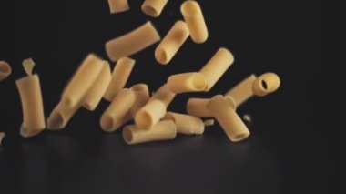 Süper yavaş çekim siyah arka planda kuru makarna bırakıyor. Yüksek hızlı bir kamerayla çekildi, 1000 fps..