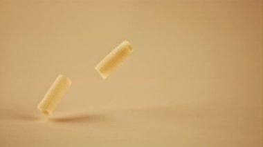 Süper yavaş çekim sarı arka planda kuru makarna bırakıyor. Yüksek hızlı bir kamerayla çekildi, 1000 fps..