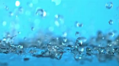 Süper yavaş çekim mavi arka planda su sıçratır. 1000 fps hızla yüksek hızlı bir kamerayla çekildi.. 