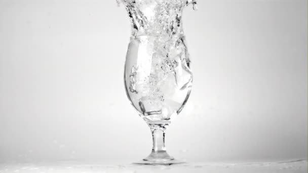 Супер замедленное движение льда падает в стакан воды с брызгами. Съемки на 1000 кадров в секунду. — стоковое видео