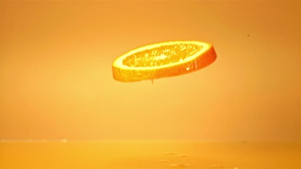 Super-Zeitlupe Stück Orange fällt in Orangensaft mit Spritzern. Gefilmt bei 1000 fps. — Stockvideo