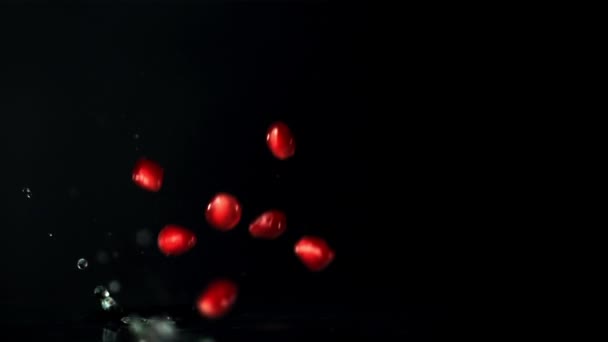 超级慢速石榴石颗粒与水花一起掉进水里。用高速相机拍摄，每秒1000英尺. — 图库视频影像