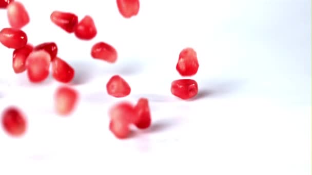 Superlangzame granaatappelkorrels vallen op tafel. Gefilmd op een hoge snelheidscamera met 1000 fps. — Stockvideo