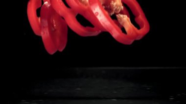 Süper yavaş çekimde kırmızı tatlı biber parçaları suya dökülüyor. Çekim 1000 fps 'de..