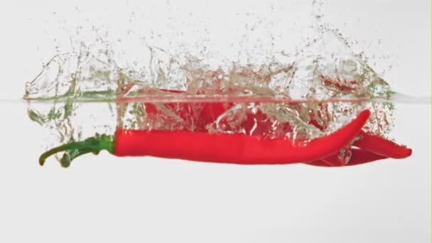 Il peperoncino al rallentatore cade in acqua con degli spruzzi. Girato su una telecamera ad alta velocità a 1000 fps. — Video Stock