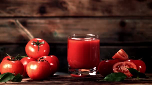 Súper vaso de cámara lenta con jugo de tomate cae sobre la mesa. Filmado a 1000 fps. — Vídeo de stock