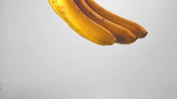 Frische Bananen fallen in Superzeitlupe mit Spritzern ins Wasser. Gefilmt bei 1000 fps. — Stockvideo