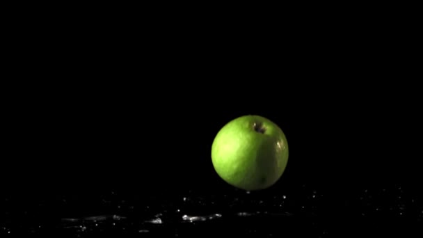 Las manzanas verdes en cámara súper lenta caen sobre la mesa con gotas de agua. Filmado en una cámara de alta velocidad a 1000 fps. — Vídeo de stock