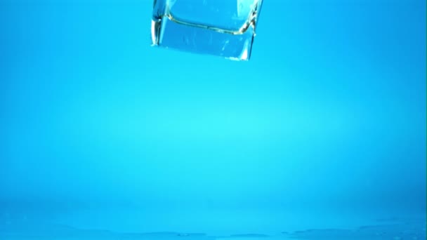 Super wolne szkło ruchome z wodą spada na stół z rozpryskami. Nagrywane z prędkością 1000 fps. — Wideo stockowe