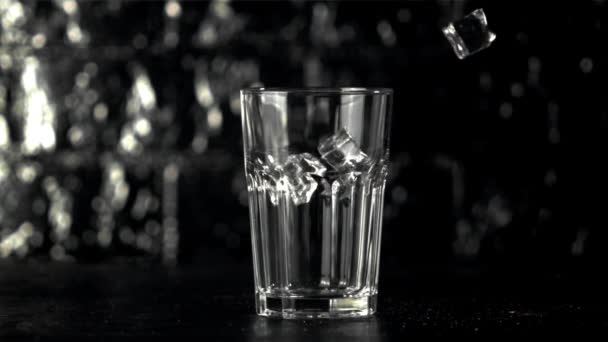 Super slow motion isbitar faller i ett glas på bordet. Inspelning på en höghastighetskamera vid 1000 fps. — Stockvideo