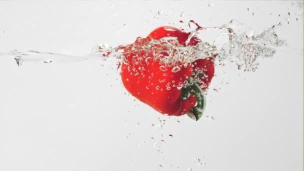 Superzeitlupe fällt eine rote Paprika mit Spritzern ins Wasser. Gefilmt mit einer Hochgeschwindigkeitskamera bei 1000 fps. — Stockvideo