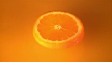 Süper yavaş çekimde bir portakal parçası portakal suyuna düşer. 1000 fps hızla çekilir..