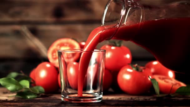 Zumo de tomate súper lento vertido de la jarra en un vaso. Filmado en una cámara de alta velocidad a 1000 fps. — Vídeo de stock