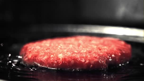Super langzaam bewegende rauwe hamburger wordt gebakken met olie spatten en hete stoom. Gefilmd met 1000 fps. — Stockvideo