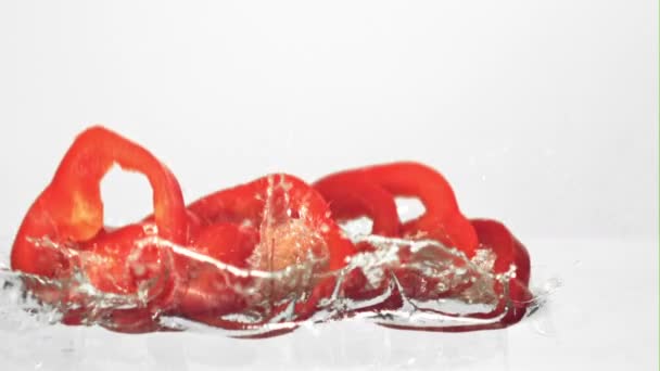 Trozos súper lentos de pimiento rojo dulce caen al agua con salpicaduras.Filmado a 1000 fps. — Vídeos de Stock