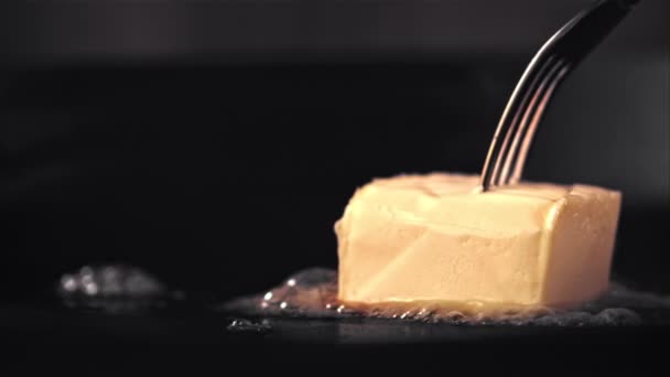 Super cámara lenta un trozo de mantequilla con un tenedor se derrite en una sartén. Filmado en una cámara de alta velocidad a 1000 fps. — Vídeo de stock
