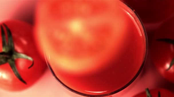 Super cámara lenta en un vaso con jugo de tomate deja caer un trozo de tomate. Filmado a 1000 fps. — Vídeo de stock
