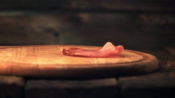 Super powolne kawałki suszonego mięsa spadają na deskę do krojenia. Nagrywane z prędkością 1000 fps. — Wideo stockowe
