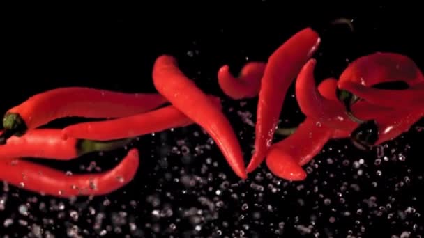 Супер медленные капсулы красного перца чили поднимаются с брызгами воды. Снято на высокоскоростную камеру со скоростью 1000 кадров в секунду. — стоковое видео