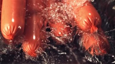 Süper yavaş çekim sosisleri suya su sıçratarak düşer. 1000 fps hızla yüksek hızlı bir kamerayla çekildi..