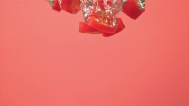 Süper yavaş hareket eden kırmızı biber parçaları hava kabarcıklarıyla suya düşer. 1000 fps hızla yüksek hızlı bir kamerayla çekildi..