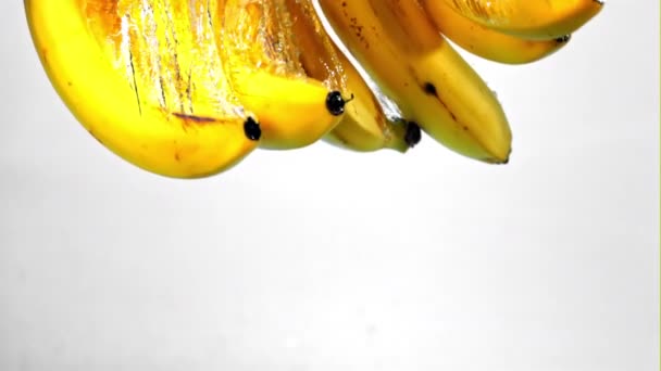 Super zpomalený pohyb pod vodou padají banány na bílém pozadí. Natočeno na vysokorychlostní kameře rychlostí 1000 snímků za sekundu. — Stock video