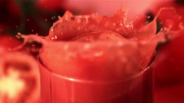 Super cámara lenta en un vaso con jugo de tomate deja caer un trozo de tomate. Filmado en una cámara de alta velocidad a 1000 fps. — Vídeos de Stock