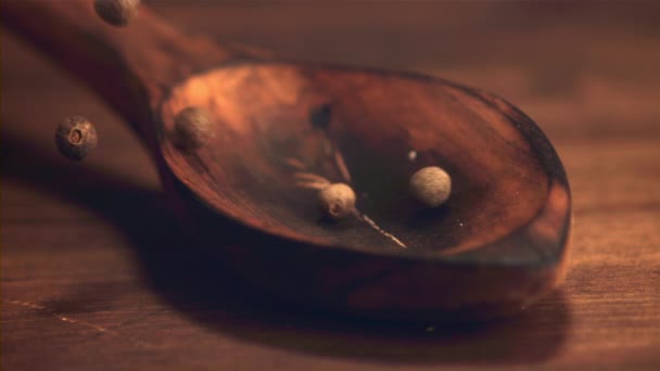 木製のスプーンで超遅い動きは黒コショウのエンドウ豆を落ちる。1000 fpsで高速カメラで撮影。木の背景に. — ストック動画