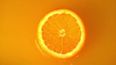 Süper yavaş çekimde bir portakal parçası portakal suyuna düşer. 1000 fps hızla yüksek hızlı bir kamerayla çekilir..