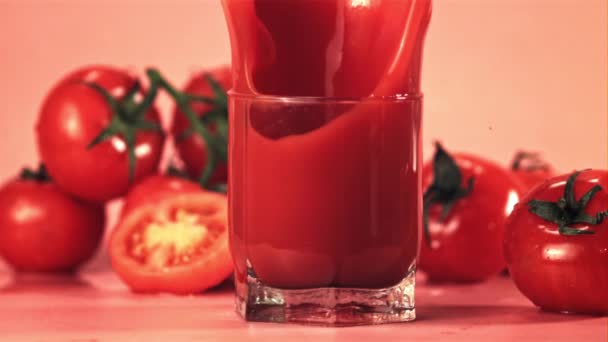 Super cámara lenta con spray cae en un vaso con jugo de tomate pedazo de tomate. Filmado a 1000 fps. — Vídeo de stock