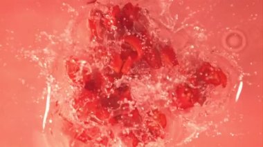 Süper yavaş çekimde dilimlenmiş kırmızı biber suya su sıçratarak düşer. 1000 fps hızla yüksek hızlı bir kamerayla çekildi..