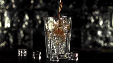 Buz küpleriyle dolu bir bardakta süper yavaş çekim kola doldurur. Çekim 1000 fps 'de..