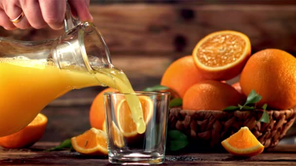 Super cámara lenta de la jarra en el vaso vierta el jugo de naranja. Filmado a 1000 fps. — Vídeo de stock